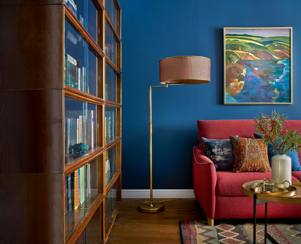 На фото: изолированная гостиная комната среднего размера в стиле фьюжн с с книжными шкафами и полками, синими стенами, паркетным полом среднего тона, телевизором на стене, коричневым полом, балками на потолке, обоями на стенах и бордовым диваном без камина с