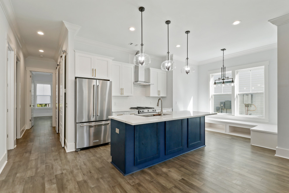 Inspiration for a mid-sized coastal galley medium tone wood floor and gray floor eat-in kitchen remodel in Atlanta with an undermount sink, shaker cabinets, blue cabinets, quartz countertops, white backsplash, porcelain backsplash, stainless steel appliances, an island and white countertops