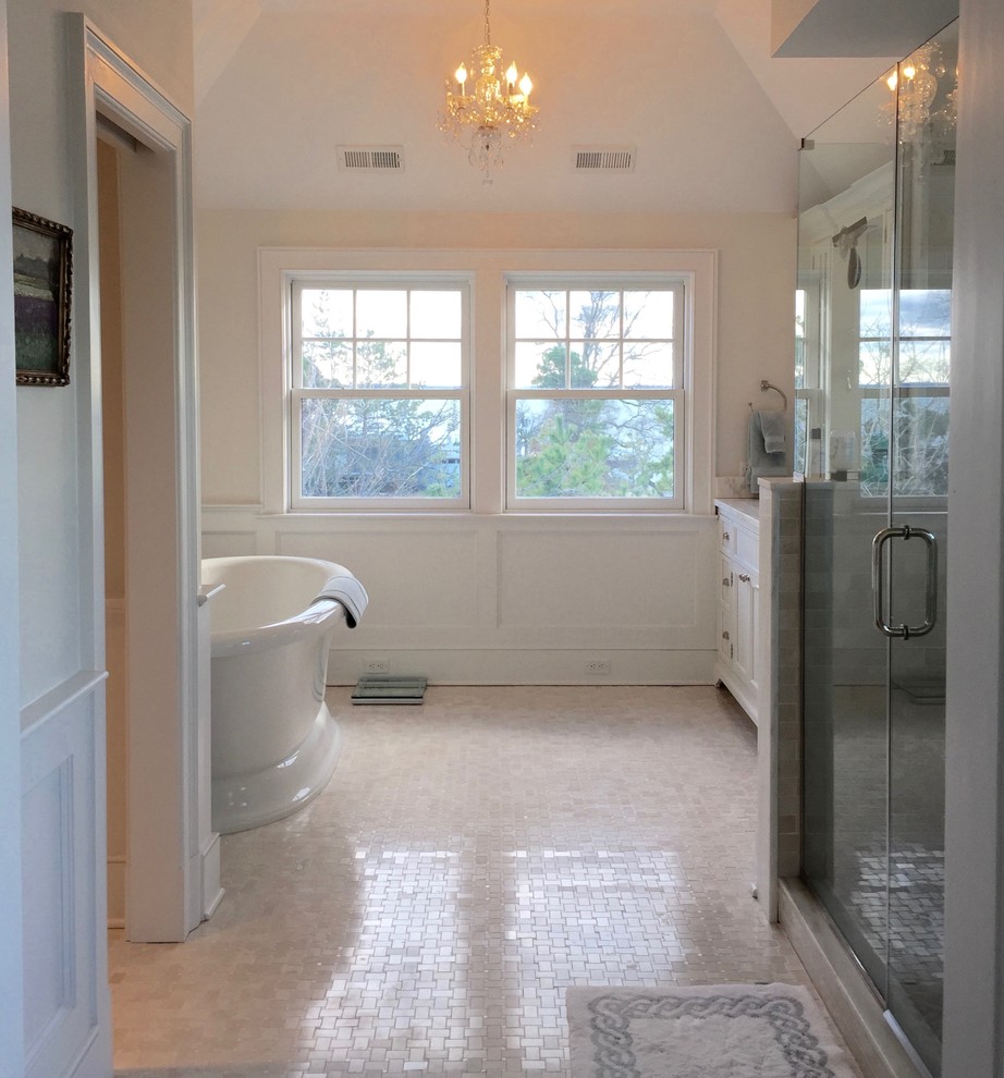 Inspiration for a large traditional master bathroom in New York with recessed-panel cabinets, white cabinets, a freestanding tub, an alcove shower, a one-piece toilet, white tile, mosaic tile, beige walls, marble floors, an undermount sink and marble benchtops.