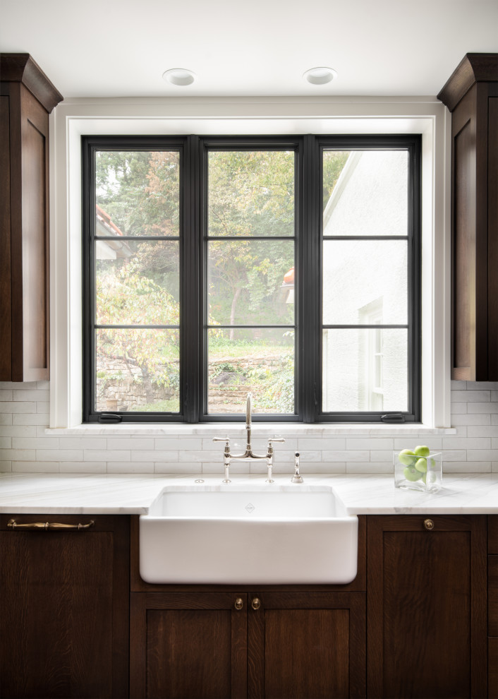 Large transitional dark wood floor and brown floor eat-in kitchen photo in Kansas City with a farmhouse sink, recessed-panel cabinets, dark wood cabinets, marble countertops, white backsplash, ceramic backsplash, paneled appliances, an island and white countertops