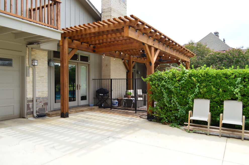 This is an example of a country backyard patio in Dallas with stamped concrete and a pergola.