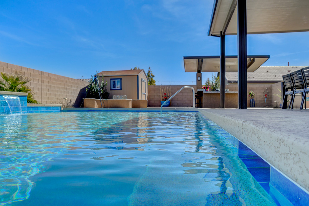 Ejemplo de piscina con fuente moderna de tamaño medio rectangular en patio trasero con entablado
