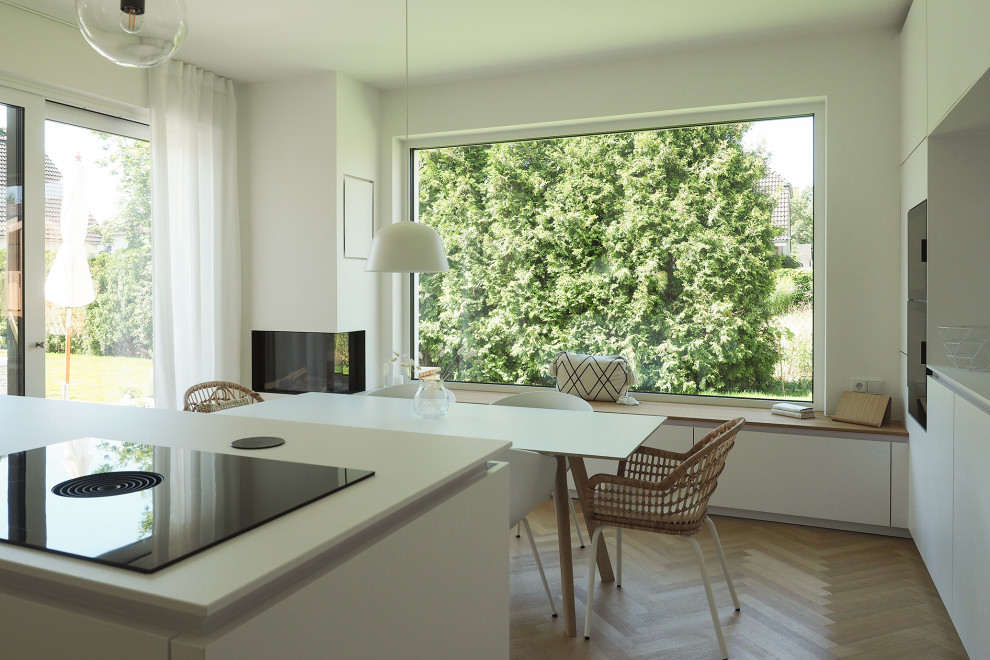 Photo of a mid-sized modern open plan dining in Berlin with white walls, light hardwood floors, a corner fireplace and a plaster fireplace surround.