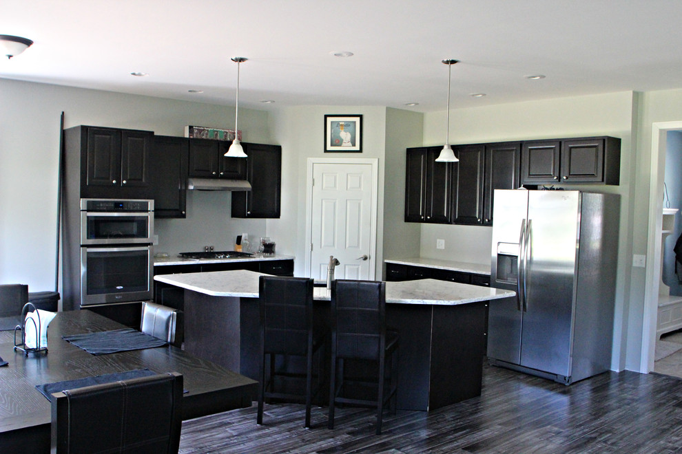 Example of a kitchen design in Omaha with raised-panel cabinets, dark wood cabinets, stainless steel appliances and an island
