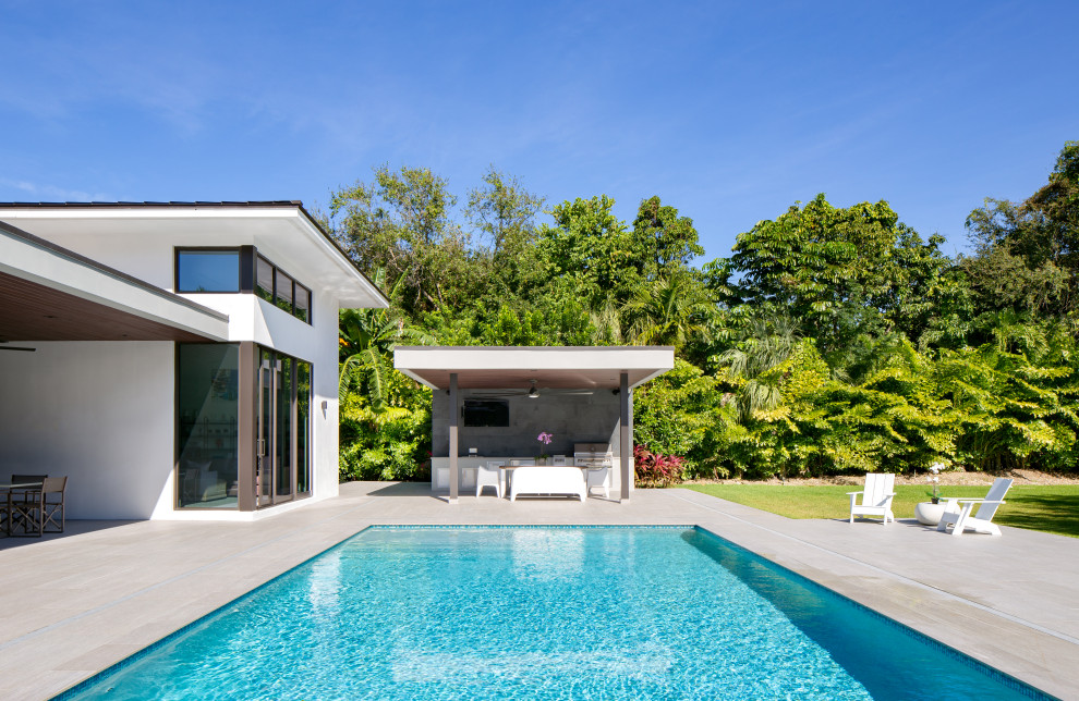 Ispirazione per una grande piscina monocorsia contemporanea rettangolare dietro casa con una dépendance a bordo piscina e pavimentazioni in cemento