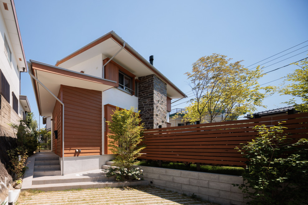 Imagen de fachada de casa blanca y gris nórdica de tamaño medio de dos plantas con revestimiento de estuco, tejado a dos aguas, tejado de metal y tablilla