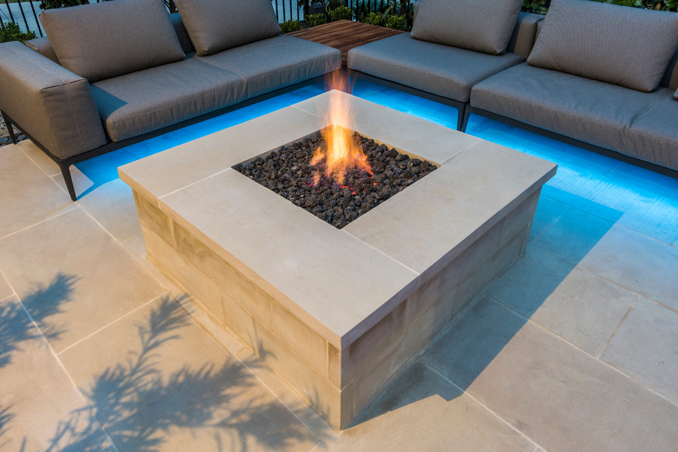 Inspiration for a mid-sized mediterranean backyard patio in Dallas with a fire feature, natural stone pavers and no cover.