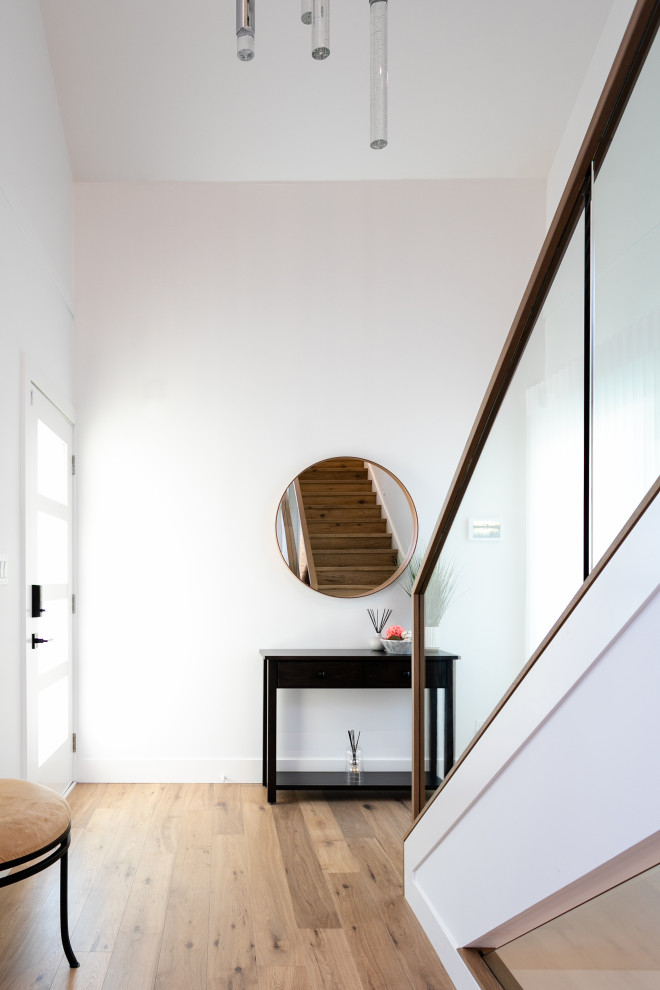 Mid-sized transitional medium tone wood floor and brown floor front door photo in Vancouver with white walls and a glass front door