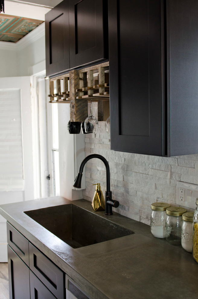 Inspiration for a mid-sized eclectic galley laminate floor eat-in kitchen remodel with an integrated sink, shaker cabinets, black cabinets, concrete countertops, white backsplash, stone tile backsplash, stainless steel appliances and a peninsula