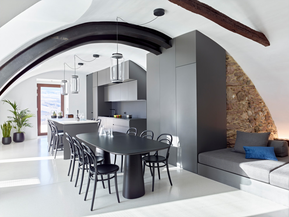 Cette image montre une très grande cuisine ouverte parallèle design avec un sol gris, un plafond voûté, poutres apparentes, un placard à porte plane, des portes de placard grises, une crédence grise, îlot et un plan de travail gris.