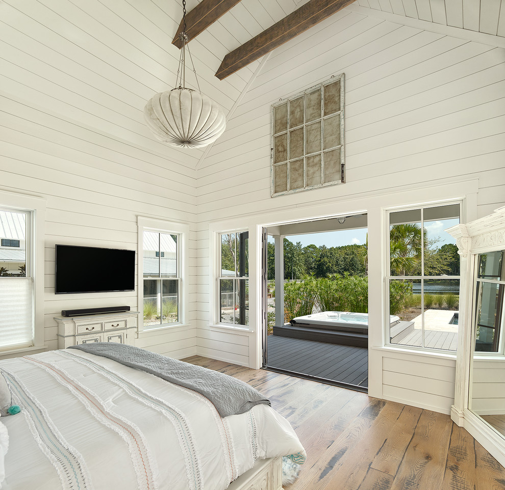 This is an example of a mid-sized country master bedroom in Charleston with white walls, light hardwood floors and brown floor.