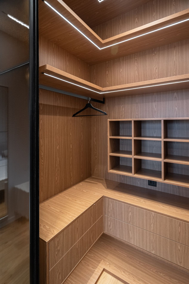 Inspiration for a mid-sized contemporary gender-neutral walk-in wardrobe in Moscow with flat-panel cabinets, medium wood cabinets and medium hardwood floors.