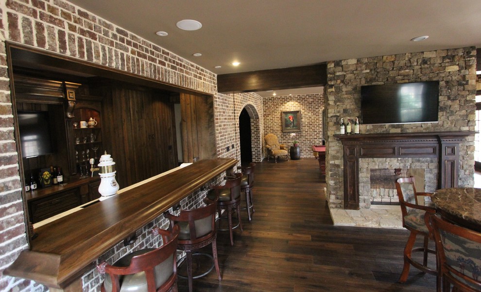 Huge transitional walk-out medium tone wood floor basement photo with brown walls, a two-sided fireplace and a stone fireplace