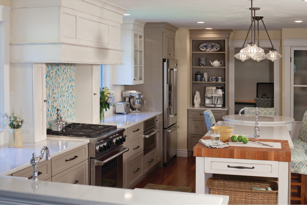 Mid-sized transitional l-shaped medium tone wood floor eat-in kitchen photo with a single-bowl sink, white cabinets, multicolored backsplash, stainless steel appliances, recessed-panel cabinets, quartz countertops, an island and mosaic tile backsplash