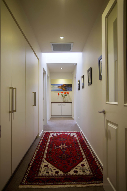 Mid-sized country hallway in Christchurch with white walls, light hardwood floors and brown floor.