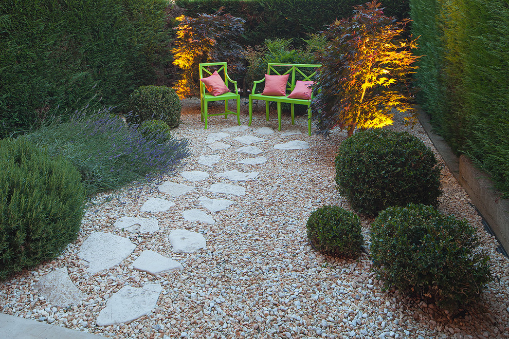 Small eclectic courtyard garden in Turin with a garden path and gravel.