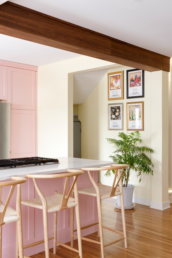This is an example of a mid-sized eclectic l-shaped eat-in kitchen in Minneapolis with a farmhouse sink, shaker cabinets, pink cabinets, quartz benchtops, green splashback, terra-cotta splashback, stainless steel appliances, light hardwood floors, with island, beige floor and white benchtop.