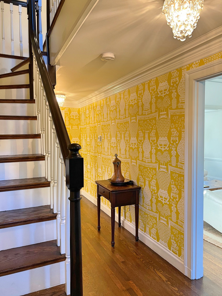 Ejemplo de hall clásico grande con paredes amarillas, suelo de madera en tonos medios, puerta simple, puerta azul, suelo marrón y papel pintado