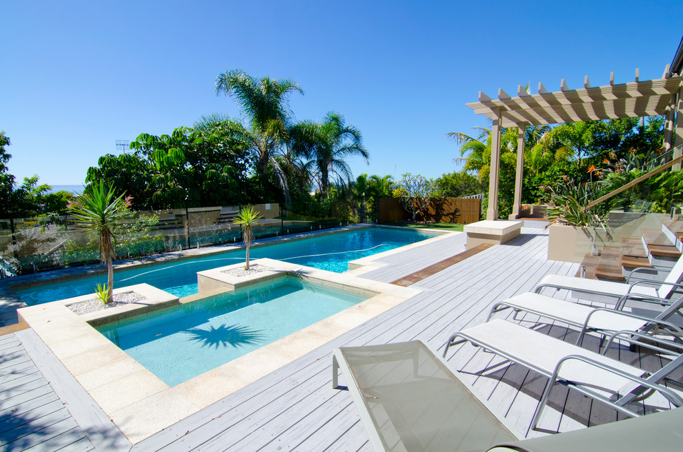 Design ideas for a large modern backyard rectangular lap pool in Sunshine Coast with a water feature and decking.