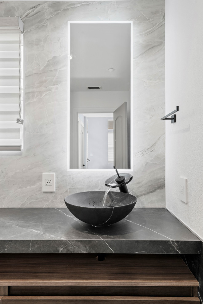 Inspiration for a small modern cloakroom in San Francisco with open cabinets, a bidet, white tiles, stone slabs, white walls, ceramic flooring, a vessel sink, engineered stone worktops, grey floors, black worktops and a floating vanity unit.