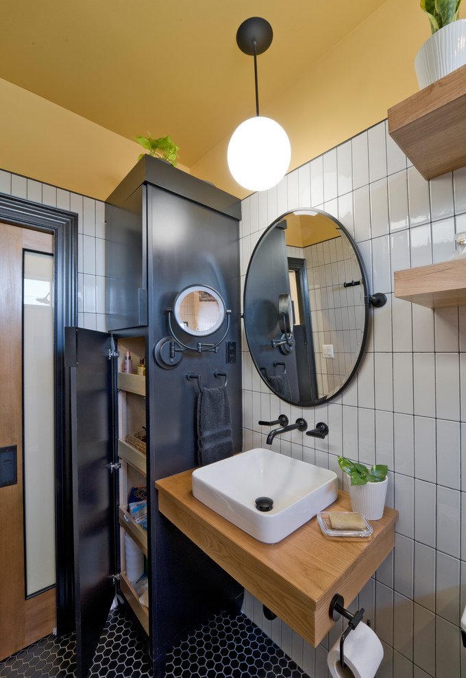 This is an example of a mid-sized contemporary master bathroom in DC Metro with shaker cabinets, medium wood cabinets, a curbless shower, a bidet, brown tile, porcelain tile, grey walls, mosaic tile floors, a vessel sink, granite benchtops, black floor, an open shower, black benchtops, a niche, a single vanity and a freestanding vanity.