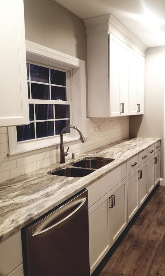 Inspiration for a transitional brown floor kitchen remodel with an undermount sink, flat-panel cabinets, white cabinets, quartzite countertops, white backsplash, subway tile backsplash, stainless steel appliances and an island