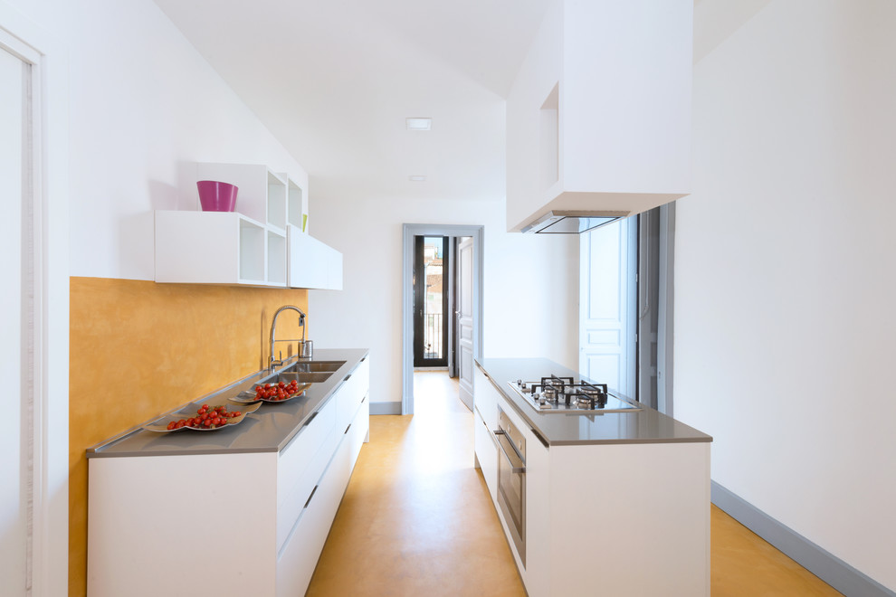 Photo of a mid-sized contemporary galley separate kitchen in Other with flat-panel cabinets, white cabinets, yellow splashback, stainless steel appliances, concrete floors, with island, yellow floor and an undermount sink.