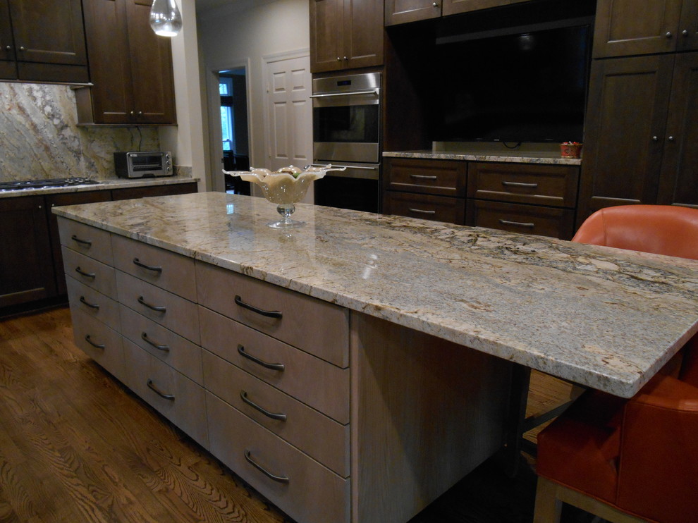 Eat-in kitchen - mid-sized transitional l-shaped medium tone wood floor eat-in kitchen idea in Birmingham with a single-bowl sink, flat-panel cabinets, medium tone wood cabinets, granite countertops, stone slab backsplash, paneled appliances, beige walls and an island