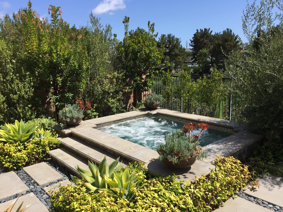 Photo of a mid-sized traditional backyard pool in Orange County with a hot tub and gravel.