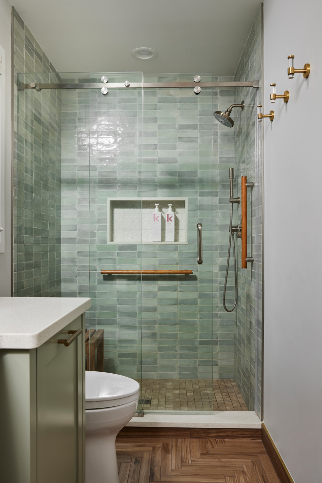 Идея дизайна: главная ванная комната среднего размера в стиле неоклассика (современная классика) с фасадами в стиле шейкер, зелеными фасадами, душем в нише, биде, зеленой плиткой, керамической плиткой, белыми стенами, полом из керамогранита, врезной раковиной, столешницей из искусственного кварца, коричневым полом, душем с раздвижными дверями, белой столешницей, нишей, тумбой под одну раковину и встроенной тумбой
