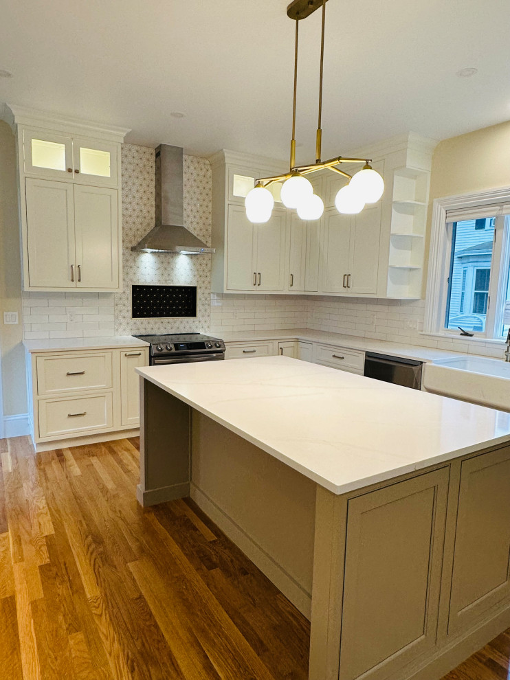 Inspiration for a large timeless l-shaped light wood floor eat-in kitchen remodel in Boston with a farmhouse sink, shaker cabinets, white cabinets, quartz countertops, white backsplash, mosaic tile backsplash, stainless steel appliances, an island and white countertops