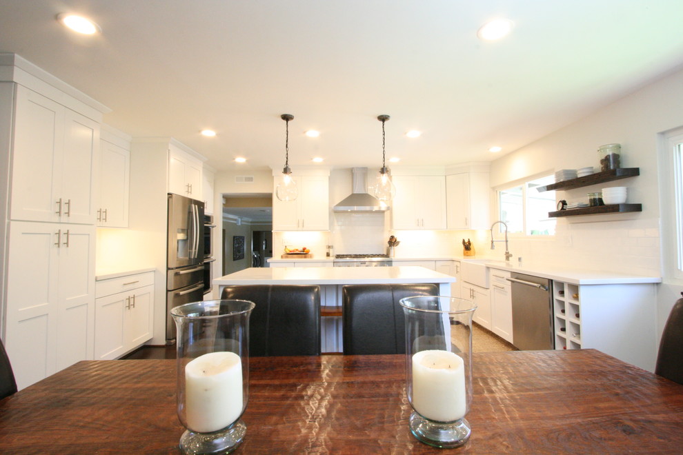 Eat-in kitchen - large transitional u-shaped dark wood floor eat-in kitchen idea in Orange County with a farmhouse sink, shaker cabinets, white cabinets, quartz countertops, white backsplash, ceramic backsplash, stainless steel appliances and an island