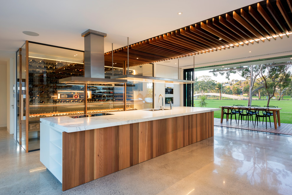 Large contemporary galley open plan kitchen in Melbourne with a double-bowl sink, marble benchtops, stainless steel appliances, concrete floors, with island, grey floor and white benchtop.