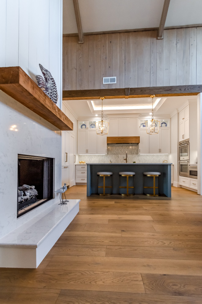 Modelo de cocina clásica renovada, pequeña, con fregadero sobremueble, armarios con paneles empotrados, salpicadero multicolor, electrodomésticos de acero inoxidable, una isla, suelo marrón, encimeras blancas y bandeja