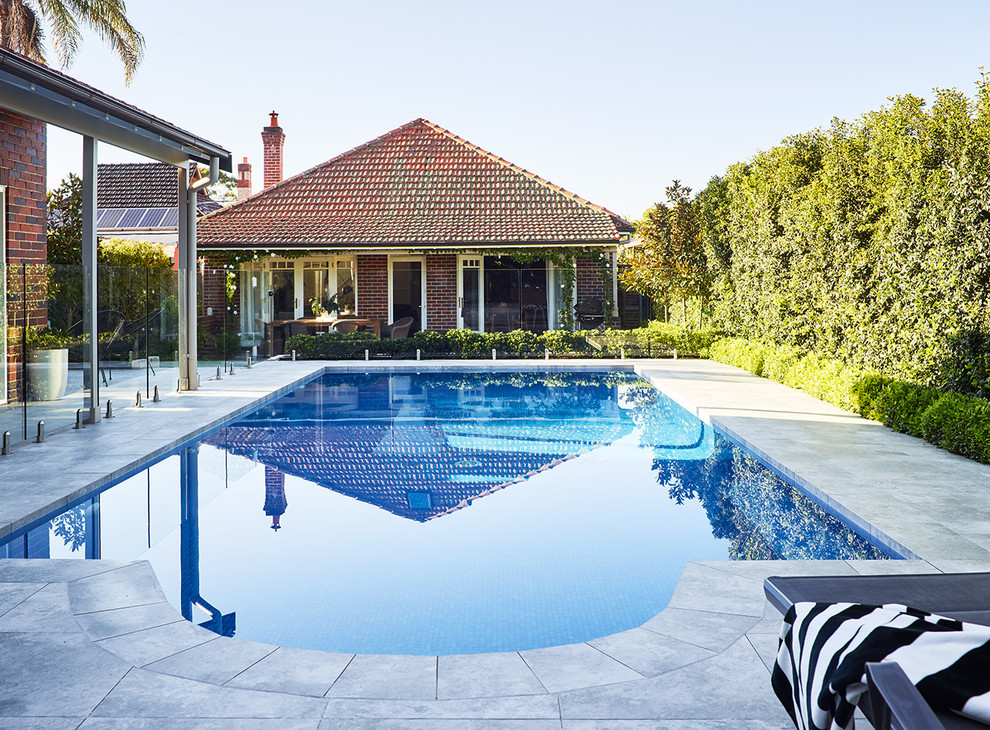 Inspiration for a large contemporary backyard pool in Sydney with natural stone pavers.