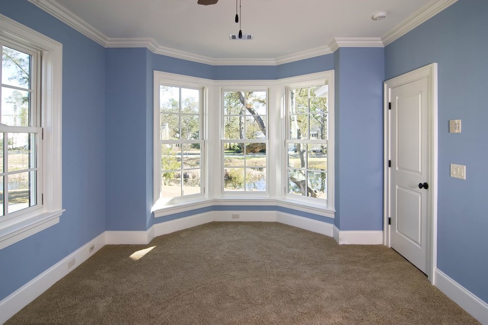 Photo of a mid-sized traditional master bedroom in New York with blue walls, carpet, no fireplace and beige floor.
