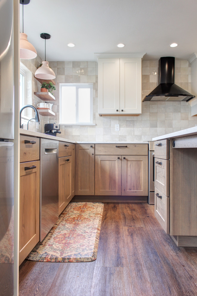 Small farmhouse l-shaped kitchen/diner in Other with a submerged sink, shaker cabinets, medium wood cabinets, engineered stone countertops, beige splashback, ceramic splashback, stainless steel appliances, vinyl flooring, an island, brown floors and white worktops.
