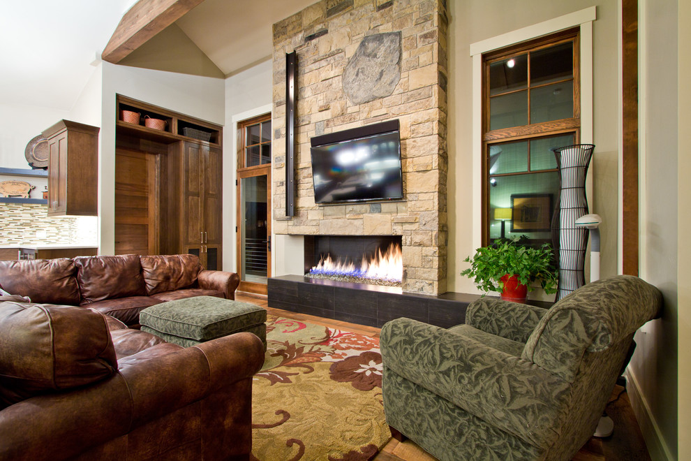 This is an example of a country formal open concept living room in Other with beige walls, medium hardwood floors, a ribbon fireplace, a stone fireplace surround and a wall-mounted tv.