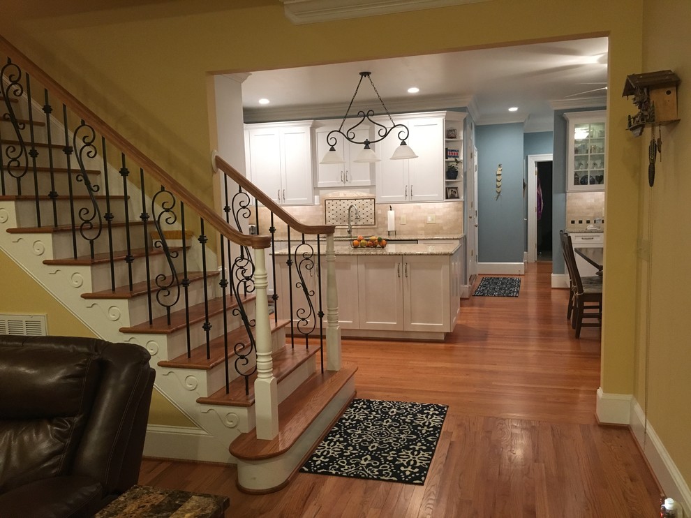 Large transitional l-shaped medium tone wood floor and brown floor eat-in kitchen photo with an undermount sink, shaker cabinets, white cabinets, granite countertops, beige backsplash, subway tile backsplash, stainless steel appliances, an island and beige countertops