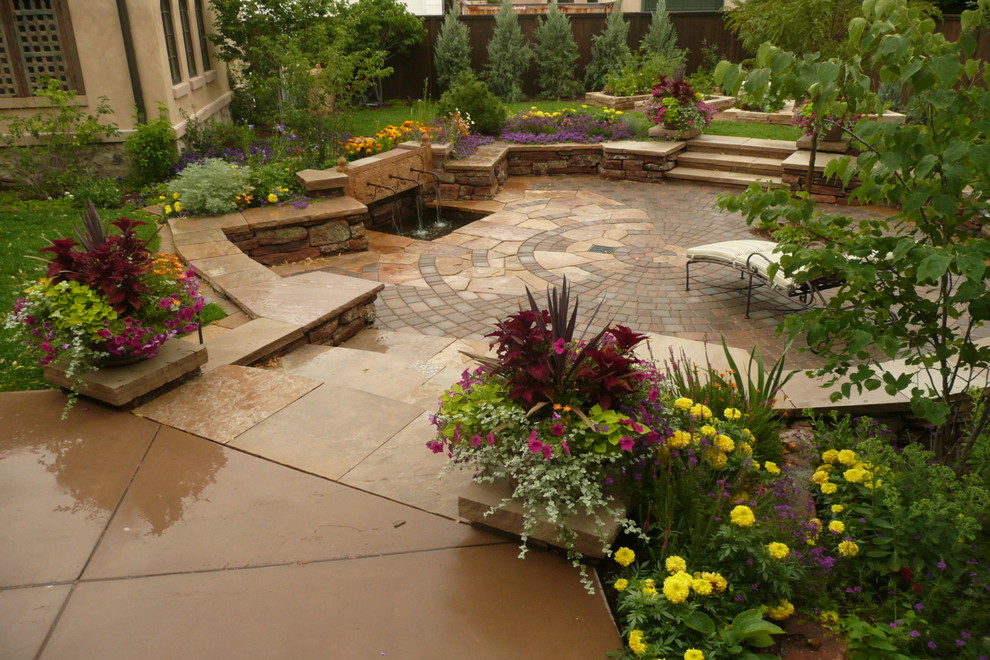Photo of a mediterranean garden in Denver with brick pavers and a water feature.