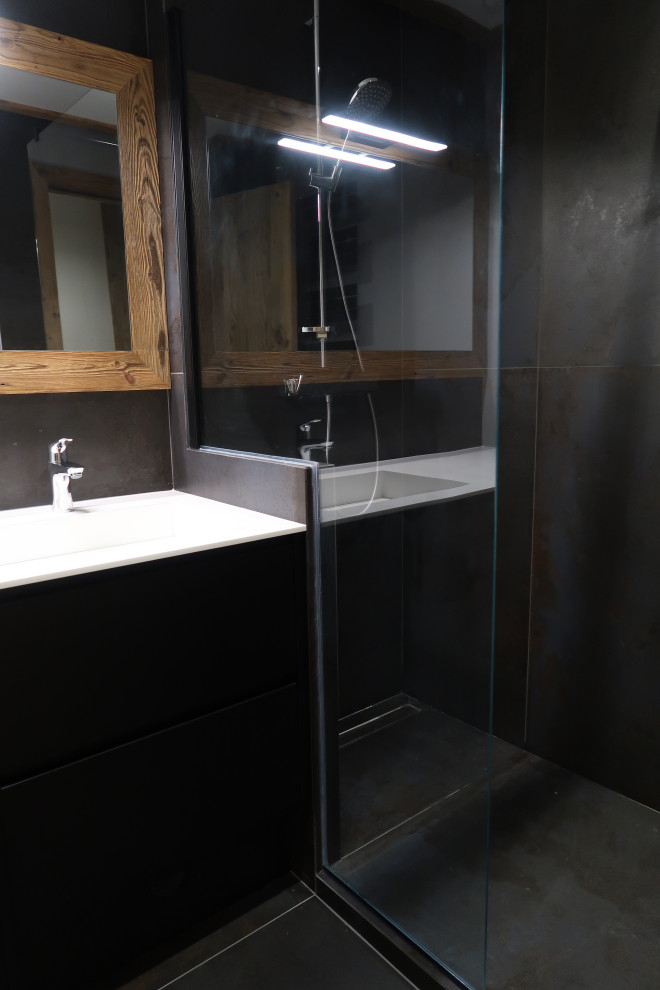 This is an example of a small country master bathroom in Grenoble with flat-panel cabinets, black cabinets, an open shower, black tile, ceramic tile, black walls, ceramic floors, a console sink, solid surface benchtops, black floor and white benchtops.