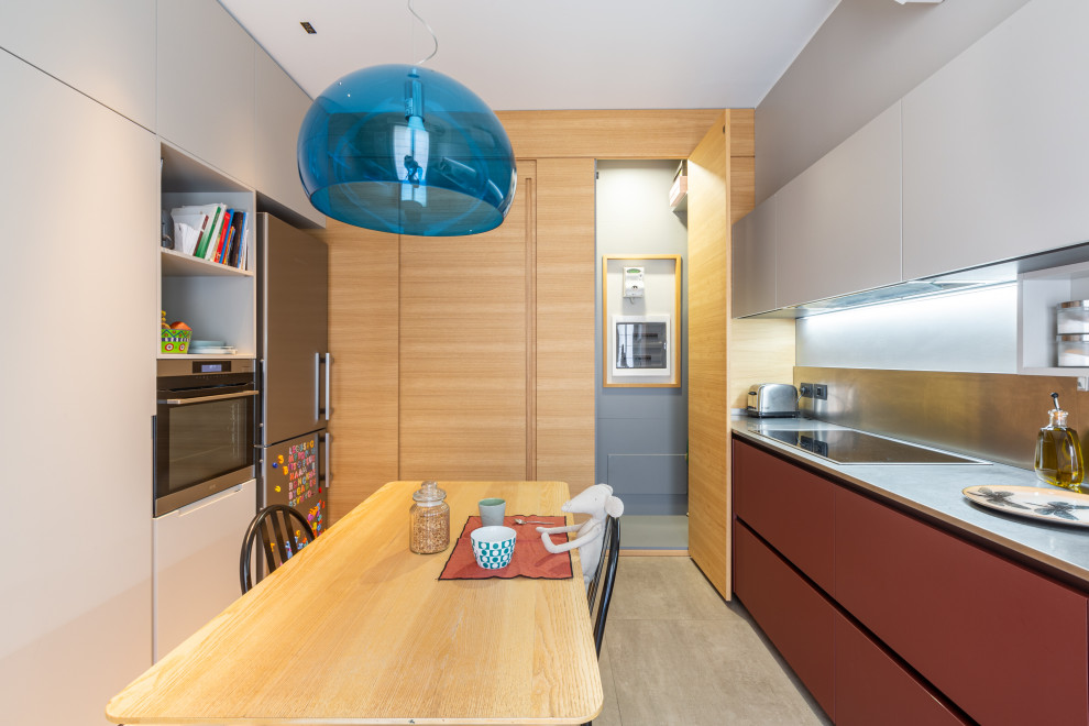 Design ideas for a large contemporary galley separate kitchen in Milan with an integrated sink, flat-panel cabinets, red cabinets, stainless steel benchtops, stainless steel appliances, porcelain floors and grey floor.