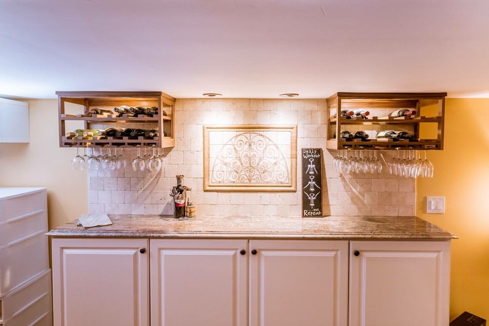 Design ideas for a mid-sized traditional single-wall wet bar in Philadelphia with no sink, raised-panel cabinets, white cabinets, granite benchtops, beige splashback, limestone splashback and brown benchtop.