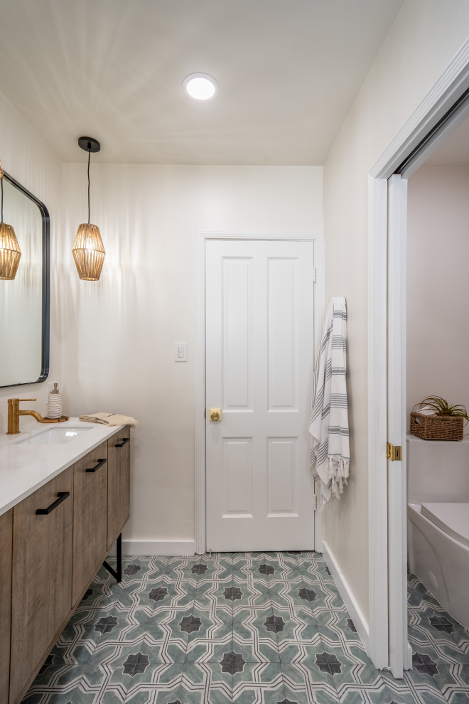 Photo of a medium sized contemporary bathroom in San Francisco with flat-panel cabinets, brown cabinets, an alcove bath, a shower/bath combination, a one-piece toilet, white tiles, ceramic tiles, white walls, porcelain flooring, a submerged sink, solid surface worktops, multi-coloured floors, a hinged door, white worktops, an enclosed toilet, double sinks and a freestanding vanity unit.