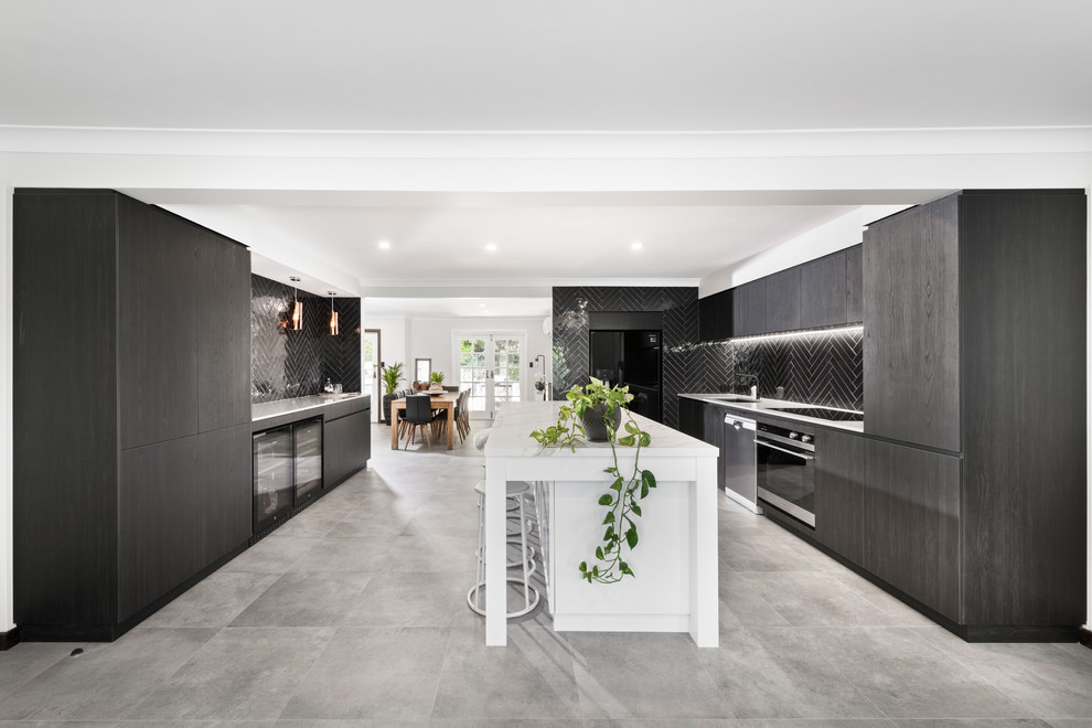 Photo of a mid-sized contemporary galley open plan kitchen in Perth with an undermount sink, flat-panel cabinets, dark wood cabinets, tile benchtops, black splashback, subway tile splashback, black appliances, cement tiles, with island, grey floor and white benchtop.