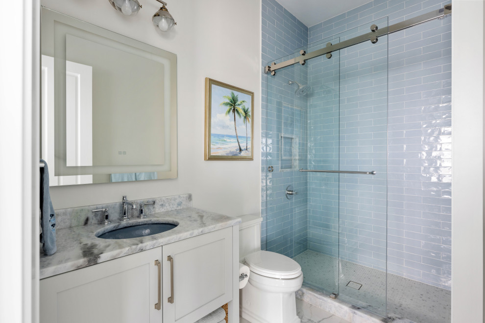 Example of a beach style blue tile mosaic tile floor, multicolored floor and single-sink alcove shower design in Tampa with recessed-panel cabinets, white cabinets, white walls, an undermount sink, gray countertops, a niche and a built-in vanity