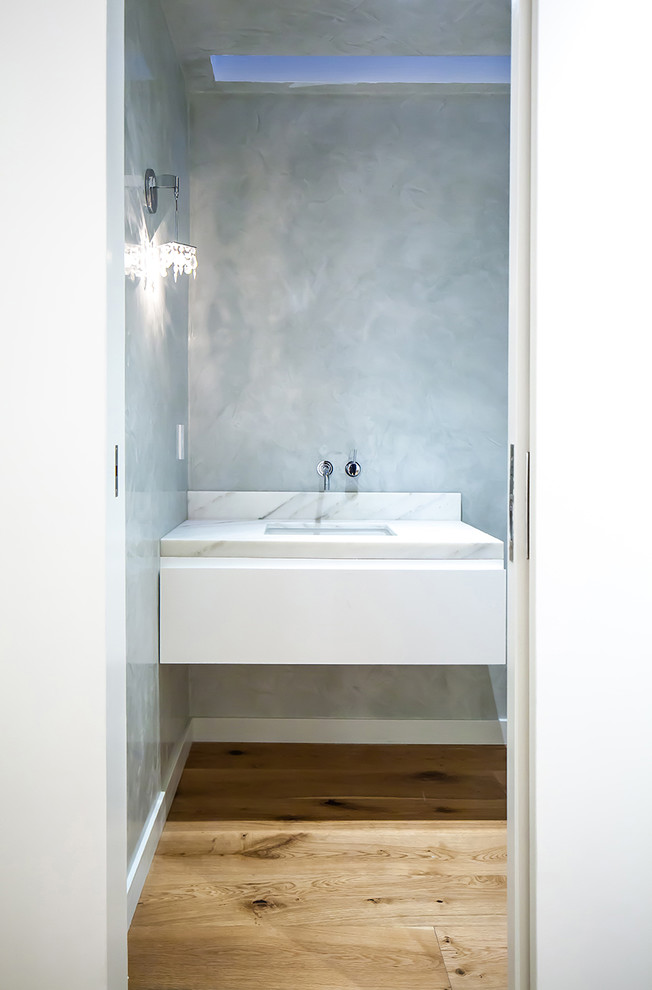 Photo of a small contemporary 3/4 bathroom in Los Angeles with flat-panel cabinets, white cabinets, gray tile, white tile, stone slab, grey walls, light hardwood floors, an undermount sink, marble benchtops, brown floor and white benchtops.