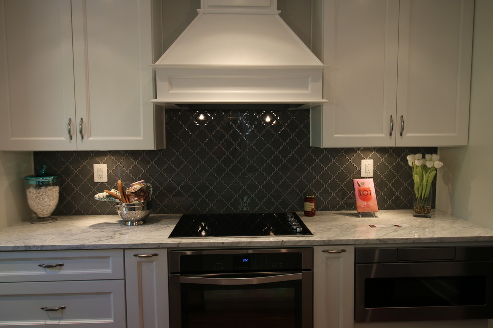 Eat-in kitchen - small transitional single-wall dark wood floor eat-in kitchen idea in DC Metro with a farmhouse sink, shaker cabinets, white cabinets, marble countertops, gray backsplash, glass tile backsplash, stainless steel appliances and an island