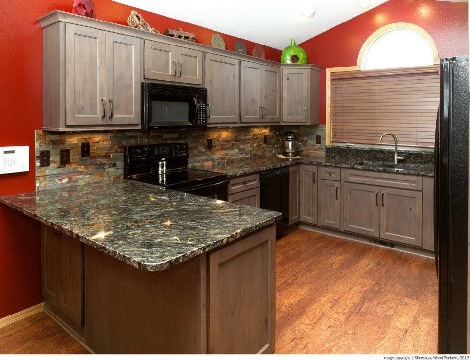 This is an example of a large country u-shaped eat-in kitchen in Other with an undermount sink, recessed-panel cabinets, distressed cabinets, granite benchtops, multi-coloured splashback, stone tile splashback, black appliances, medium hardwood floors, a peninsula and brown floor.