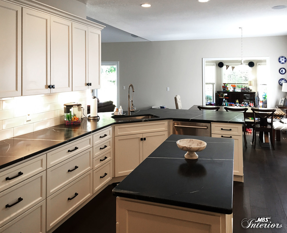 Eat-in kitchen - mid-sized transitional u-shaped dark wood floor and brown floor eat-in kitchen idea with an undermount sink, recessed-panel cabinets, white cabinets, soapstone countertops, white backsplash, subway tile backsplash, stainless steel appliances and an island